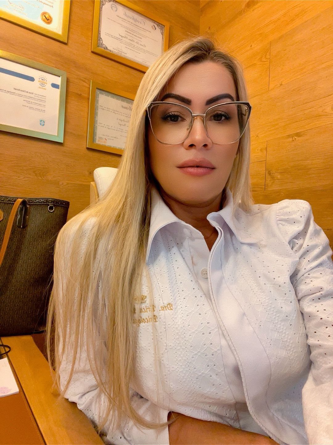 Dra. Érica Rangel em seu consultório, com os diplomas ao fundo