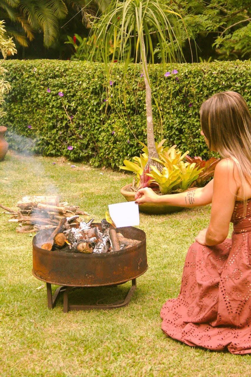Ritual de recomeço: uma participante queima um papel na fogueira do jardim