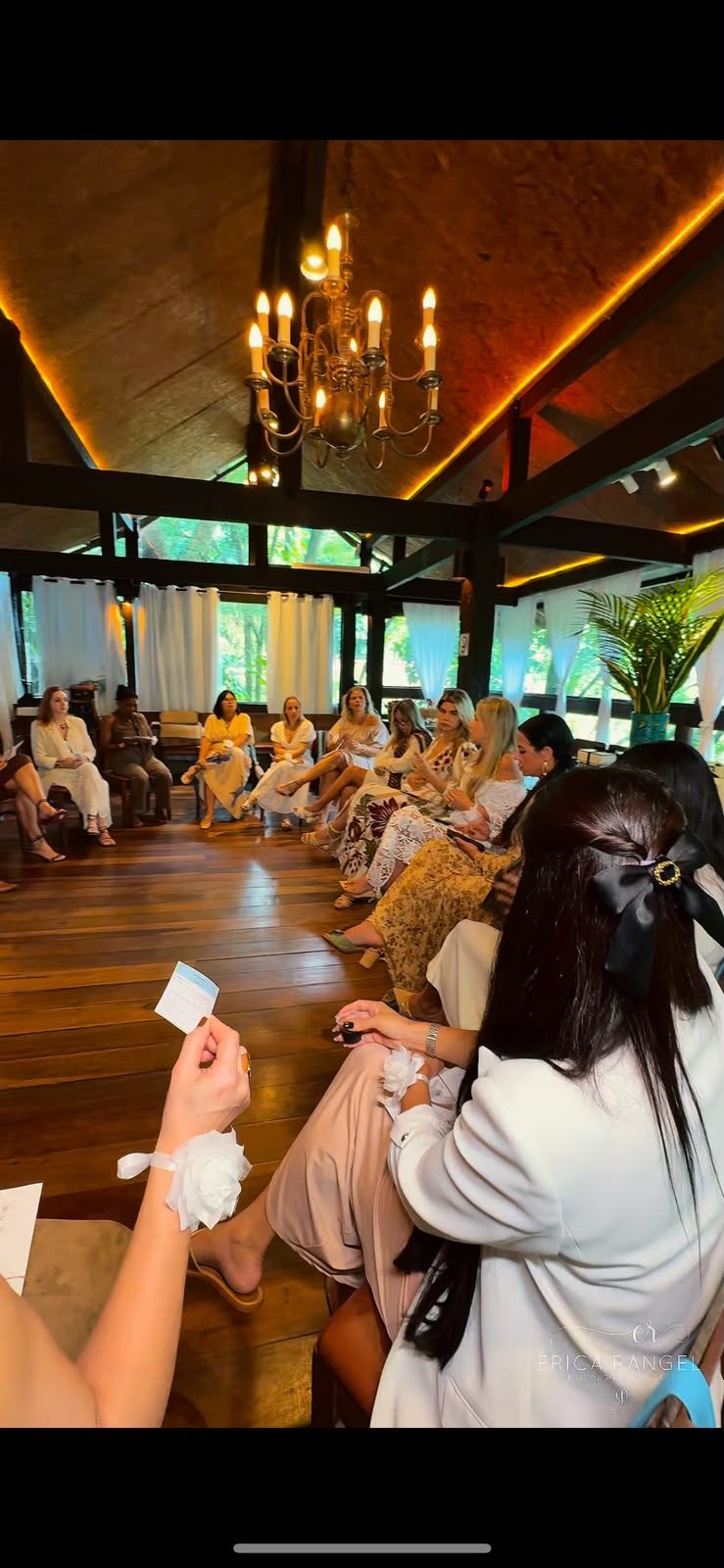 Roda de conversa em um salão de madeira com lustre